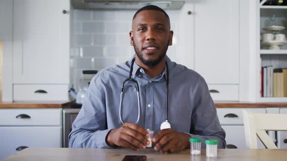 Portrait of african american doctor holding medication container talking while having a video call a