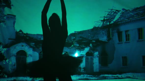 Ballerina Silhouette Dancing Raising Leg Spinning at Background of Ruined Bombed Building Photo