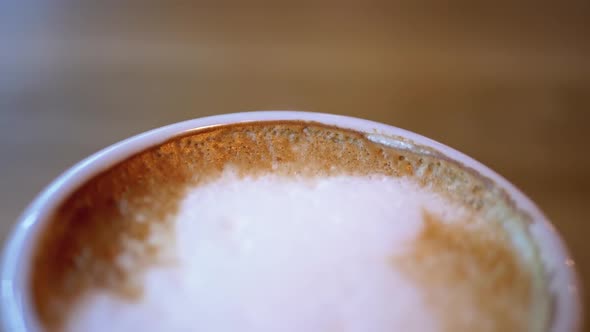 Cup of Cappuccino with White Foam on the Wooden Table in the Restaurant. Close-up