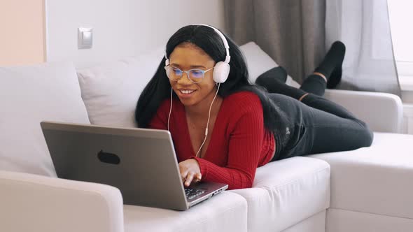 Young African Woman in Headphones with Laptop Working at Home