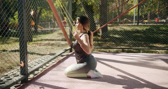 Sporty Woman Doing Exercises with Resistance Band Outside