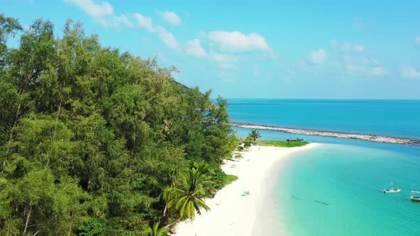 Peaceful exotic beach with beautiful palm trees bent over white sand washed by calm turquoise lagoon