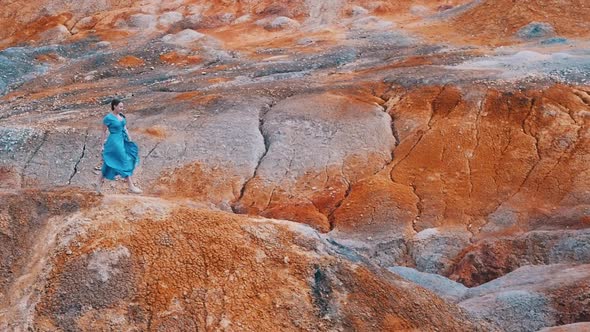 Young Woman Traveler Running on an Orange Clay Mountains