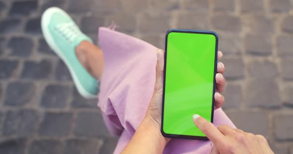 Crop View of Female Person Holding and Scrolling Smartphone with Mockup Screen While Sitting at