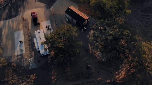 Aerial pull back shot of an RV Trailer in an RV Park at sunset showing the setting sun.