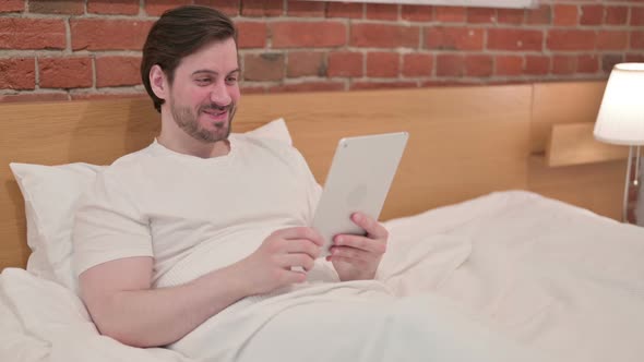 Casual Young Man Doing Video Call on Tablet in Bed