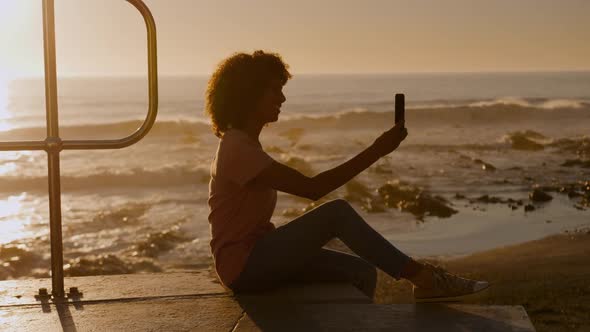 Woman taking selfie on beach at sunset