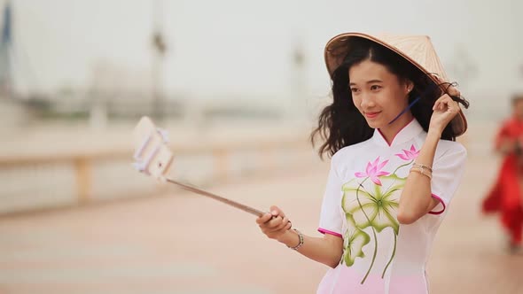 The Girl in the Vietnamese National Traditional Costume Photographs Herself Using the Phone