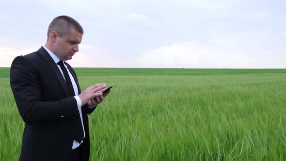 Angry Businessman Talking on a Smartphone in the Middle of the Field