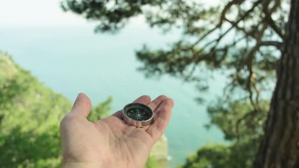 Tourist Compass on a Male Palm in the Background Sea Waves