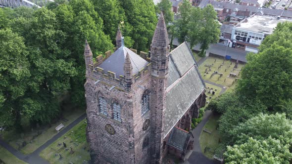 Aerial view above rural English town countryside idyllic church bell tower and graveyard