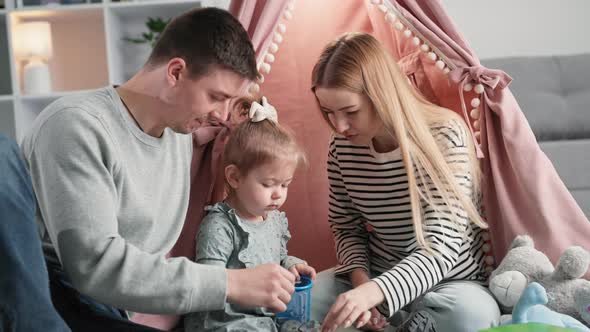 Family Fun Joyful Woman and Man Playing and Developing Motor Skills of Cute Little Girl with Wooden