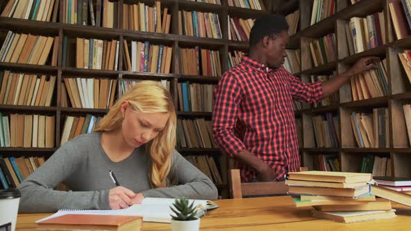 White Girl and Black Guy Surrounded By Books in Library