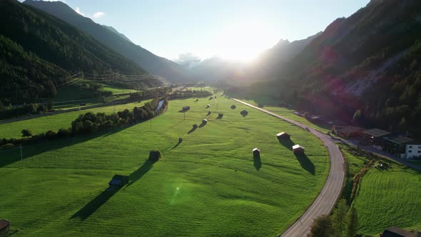 Aerial View of Empty Road in Austrian Valley Between Green Fields at Sunset Alps