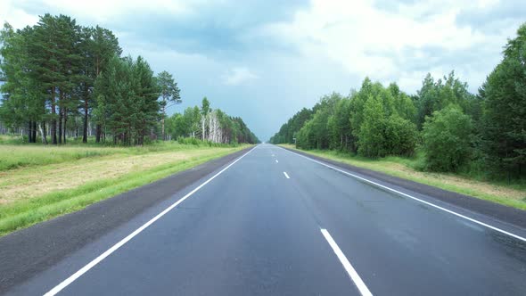 Aerial View of Scenic Road Between Green Trees with Pines on a Sunny Summer Morning