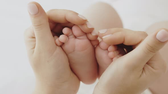 Caring Mom Holds Baby Feet in Her Hands Forming a Heart Shape