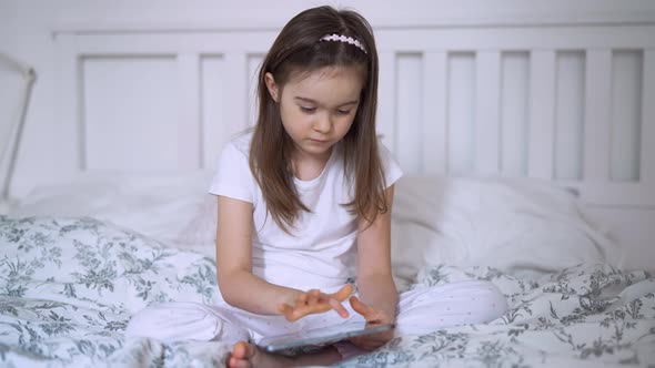 Girl Browsing Tablet on Bed