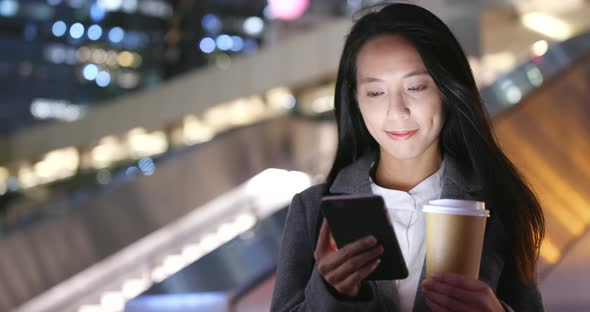 Asian businesswoman use of mobile phone and hold with hot coffee