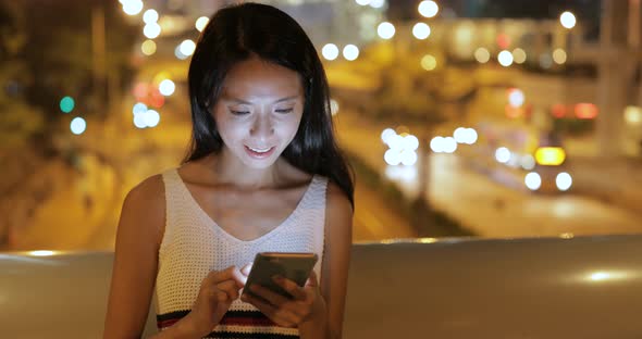 Woman using mobile phone in Hong Kong city at night 