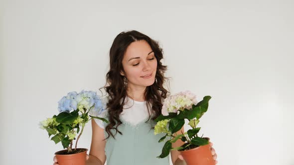 Beautiful Young Woman Florist with Flowers on White Background Smiling at Camera