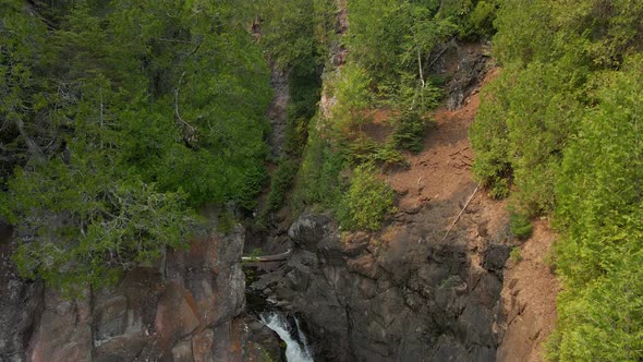 aerial view of River with a waterfall in the middle of a canyon in Northern Minnesota during summer