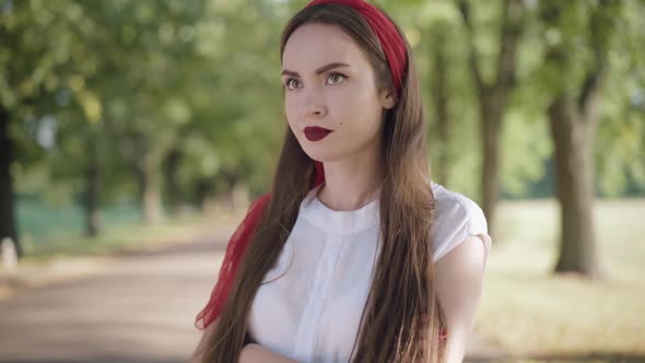 Portrait of Gorgeous Young Caucasian Woman Waiting for Boyfriend in Sunny Summer Park, Dissatisfied