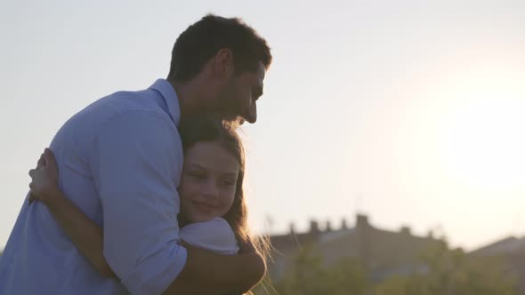 Side View of Preteen Girl Running and Hugging Father Outdoors