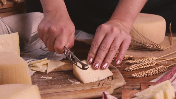 Women cut fresh homemade cheese on a wooden board with a cheese knife close up