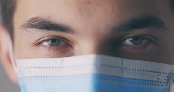 Young Male in Medical Mask Opening Eyes and Looking Straight to Camera