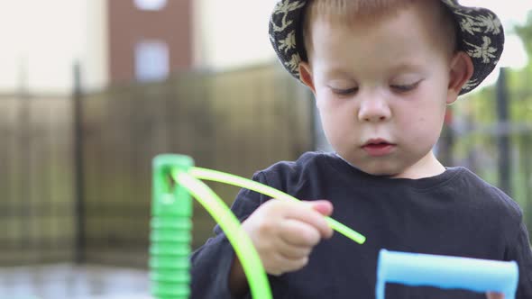 Funny Caucasian Child Kid Boy in Black Shirt and Hat Playing Outside with String