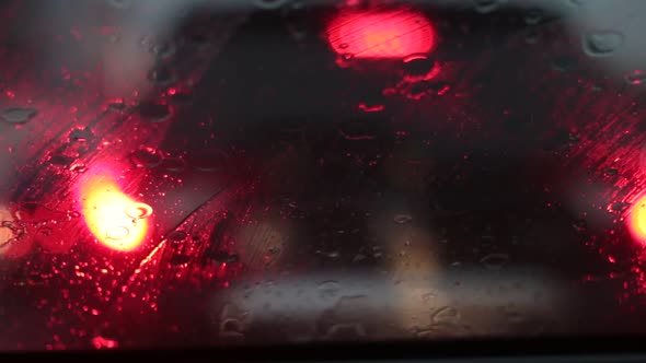 Rain falling on car windshield view. Drive car on traffic jam street