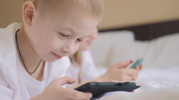 Cute Girl and Sweet Boy Playing in Video Game on Two Smartphones