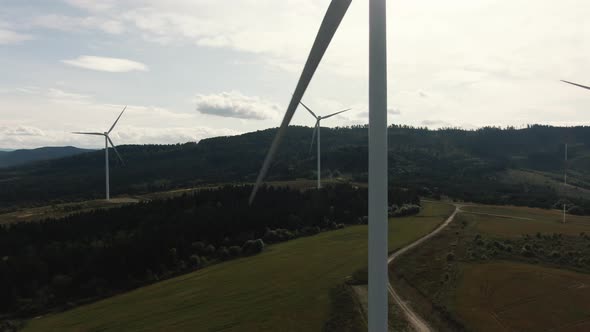 Aerial Drone Shot of Wind Turbines in the Forest Near the Sea at Sunset. Shot in  (UHD).