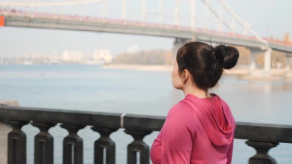 Close up view of young chubby female doing nordic walking along city river and bridge