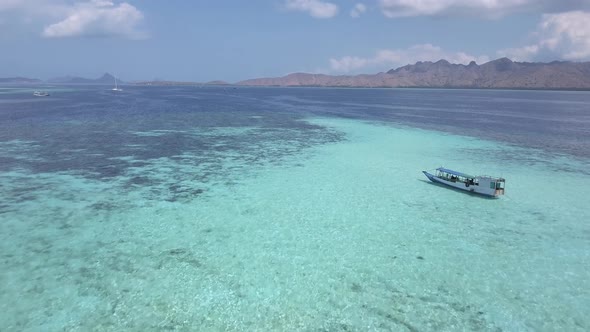 Aerial drone shot of a traditional South Asian boat sailing through the sea with clean and turquoise