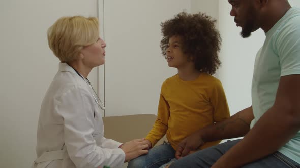 Positive Pretty Female Pediatrician Talking with Lovely Little Patient During Medical Checkup