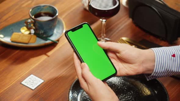 Woman Using Smartphone with Chroma Green Screen Online Menu in Cafe