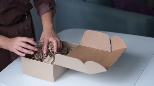 Woman is Packing Jars of Cosmetics in a Box to Send a Parcel Through a Delivery Service