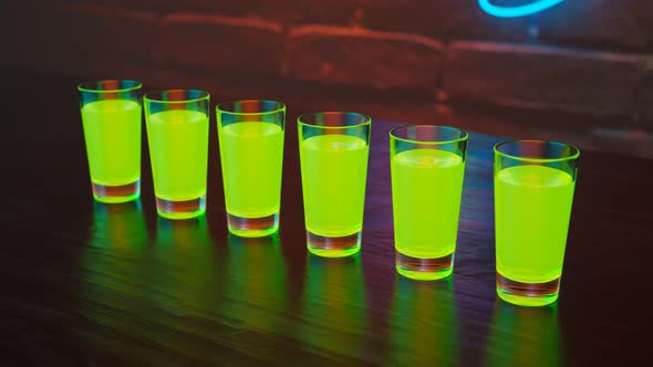 Green shots on the bar. Colourful alcoholic drinks on the table in a nightclub.