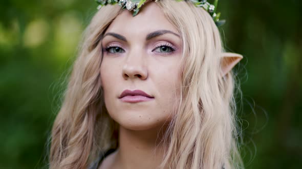 Portrait of Young Woman in Cosplay Elf Clothes and with Make-up on Green Background. Fantastic Look