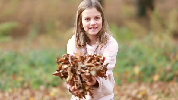 Cute girl throwing leaves in park