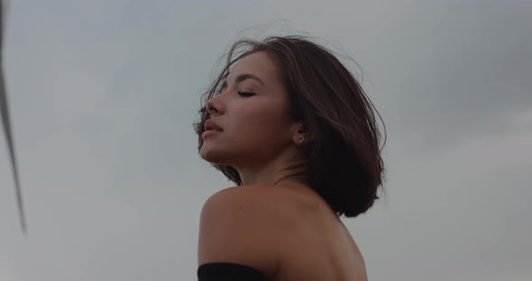 Woman Posing Against Dramatic Sky Background Gazing at Camera