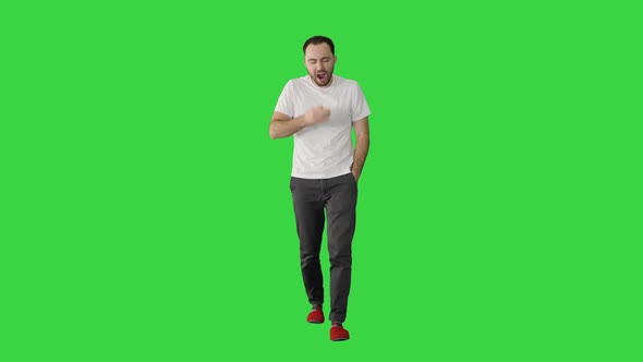 Sleepy Male in White T-shirt Yawning and Rubbing Eyes While Walking on a Green Screen, Chroma Key.