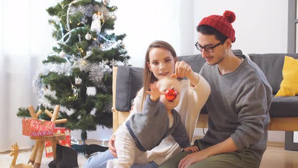 Young Happy Joyful Family. Mother, Father and Baby Boy Son Dressed in Sweaters Having Fun Near