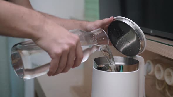 FIlling White Modern Electric Kettle with From the Glass Bottle