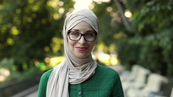 Young Muslim Woman Wearing Hijab Head Scarf in City Park While Looking at Camera