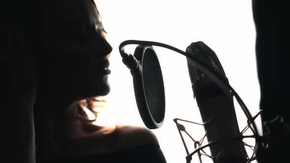 Young woman recording a song in a professional recording studio. Female vocal. Black and White.