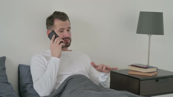 Man Talking on Call on Smartphone in Bed