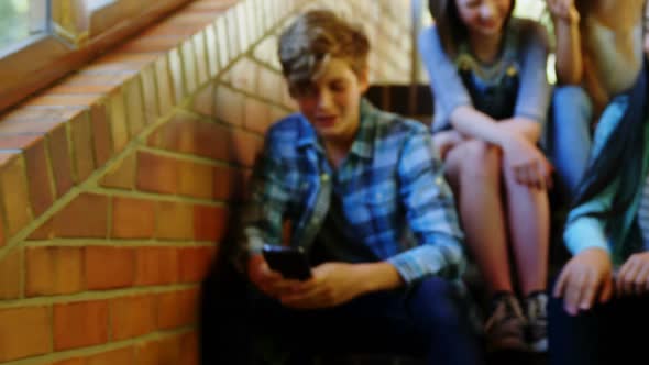 School friends bullying a sad boy in school corridor