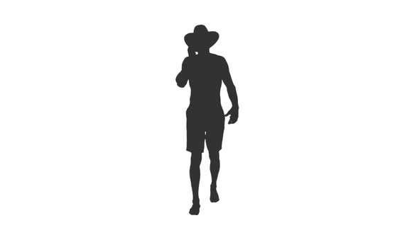 Silhouette of Young Man in Cowboy Hat Walks and Talking on Phone alt